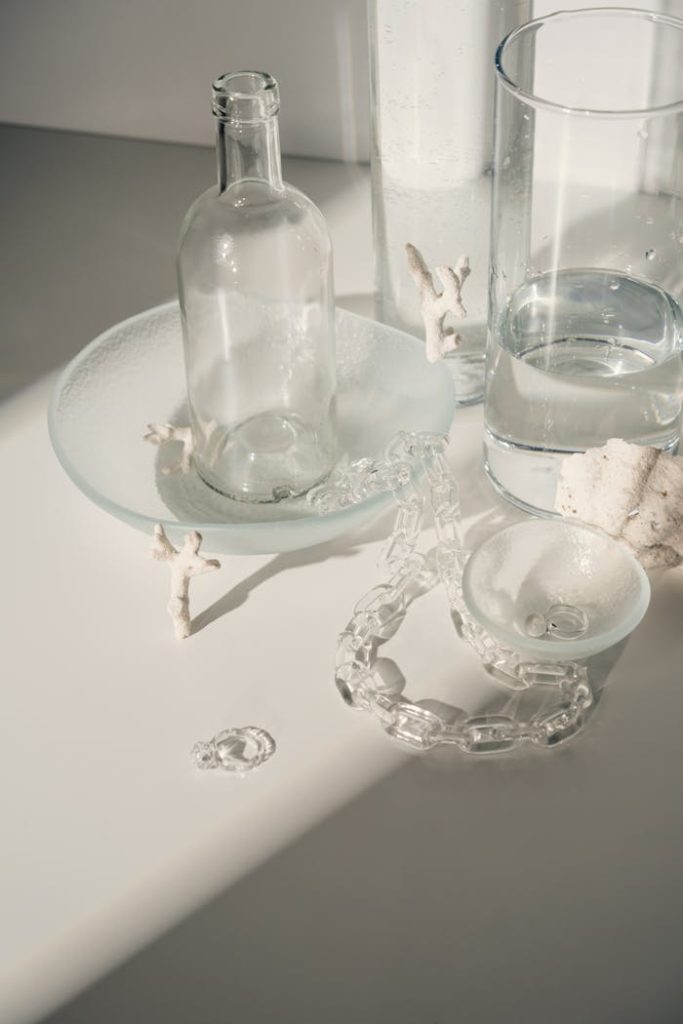 A minimalist arrangement of glass bottles and small sculptures in soft lighting.